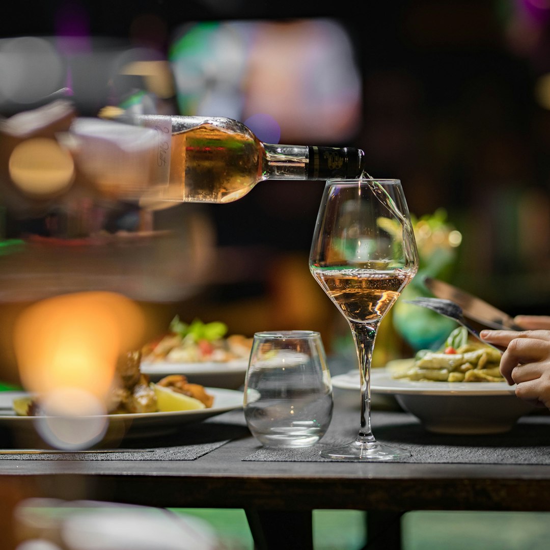 A person pouring wine into a glass at a table